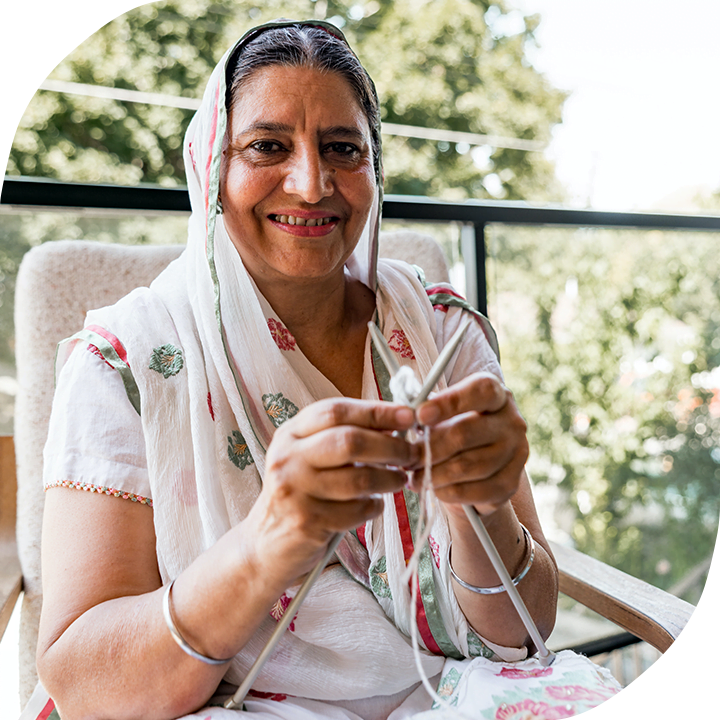 A Sikh woman smiles as she knits.